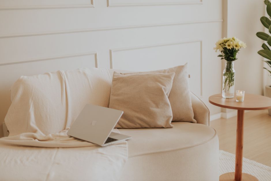 Um espaço de convivência minimalista e sereno com um laptop e flores, perfeito para trabalho remoto.