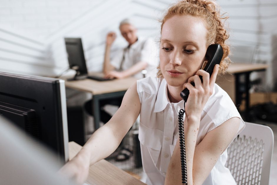 Empresária concentrada fazendo uma chamada telefônica em sua mesa em um escritório moderno.
