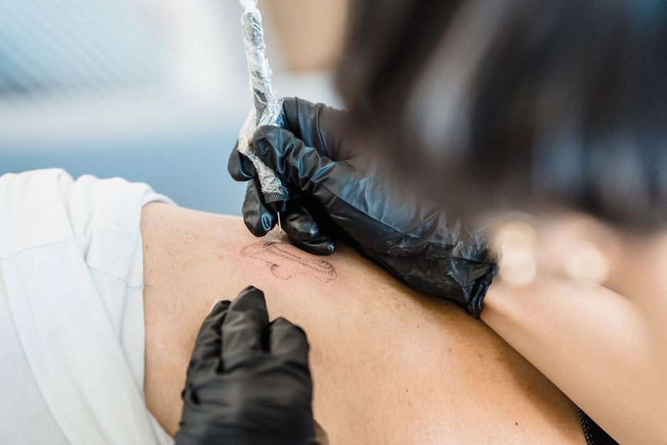 Close de um tatuador aplicando uma tatuagem com habilidade, destacando precisão e arte.